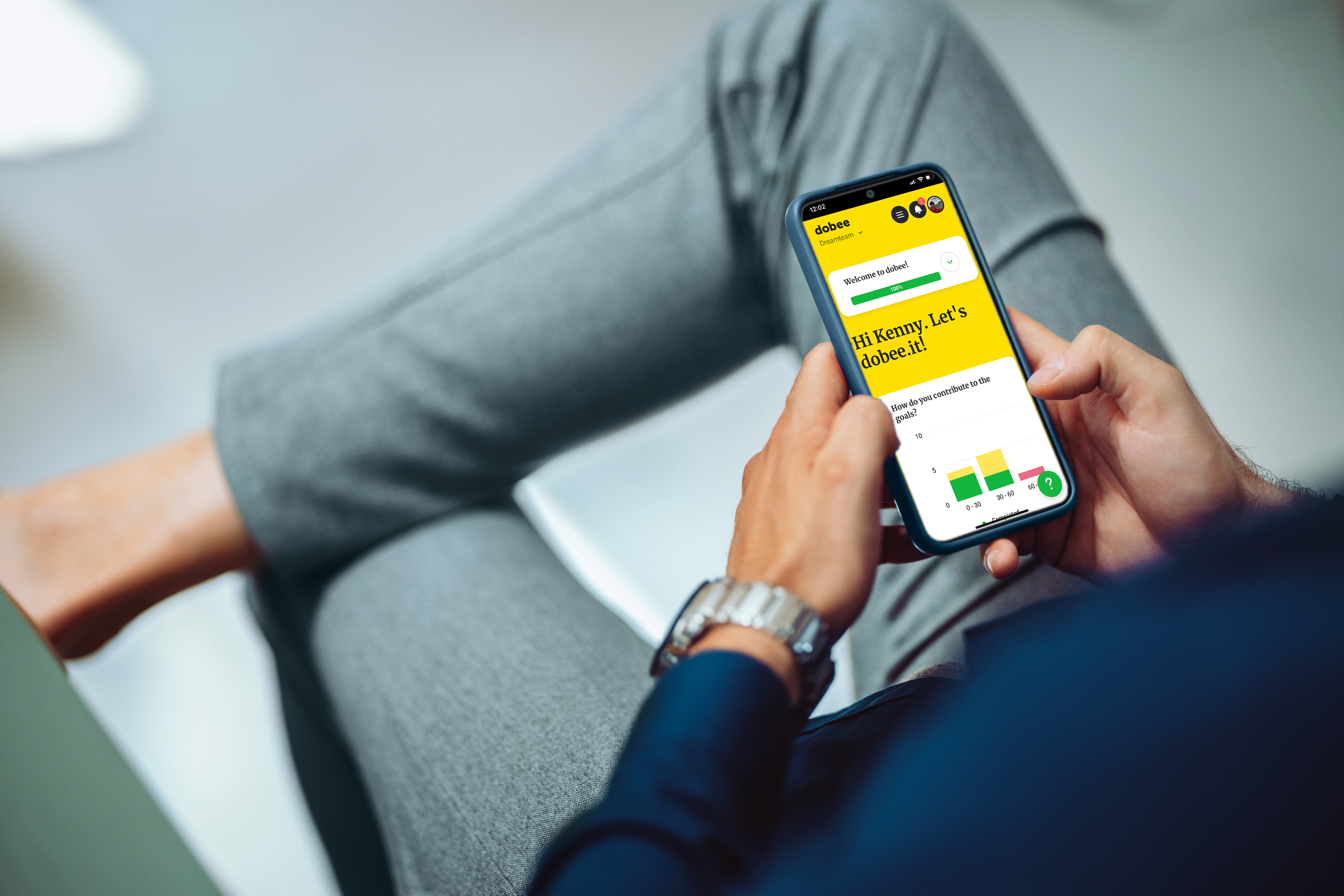 en mann sitter med en iphone i hendene der okr verktøyet dobee er oppe på skjermen